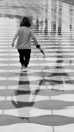 Rear view of woman walking on umbrella during rainy season