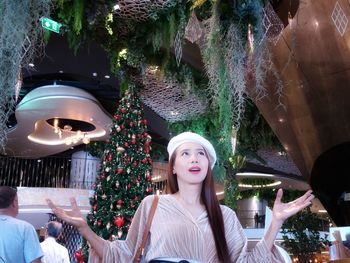 Smiling woman standing against christmas tree