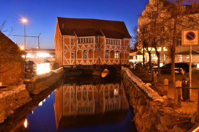 Canal by illuminated bridge against sky at night