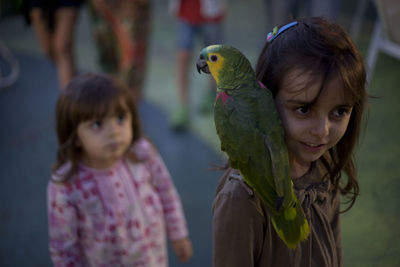 Close-up of cute girl with parrot on shoulder