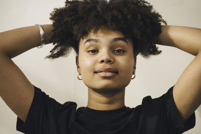 Young woman with hand in hair against beige background