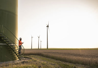 Male technican looking at wind turbine while standing on staircase