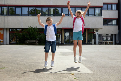 A boy and a girl happily jump up near the school. joy at the beginning of the school year 