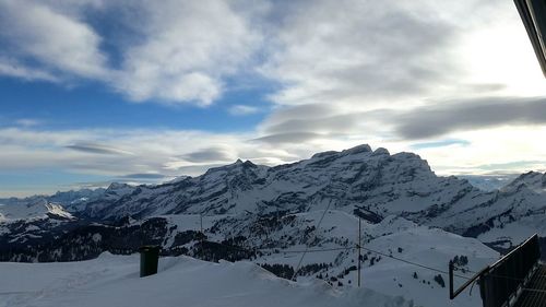 Scenic view of snow covered mountains against cloudy sky