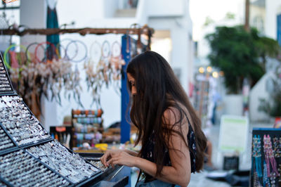 Side view of young woman standing at shop