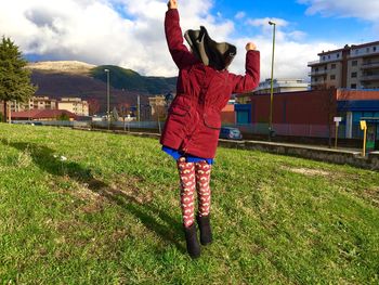 Rear view full length of girl standing on field against sky