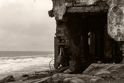 Abandoned building by sea against sky
