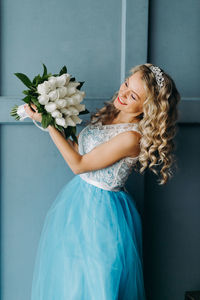 Midsection of woman wearing blue dress holding bouquet