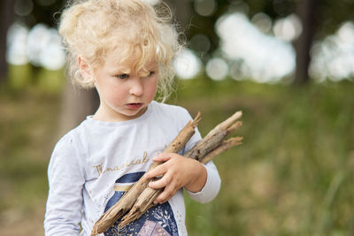 Portrait of cute baby girl holding leaf outdoors