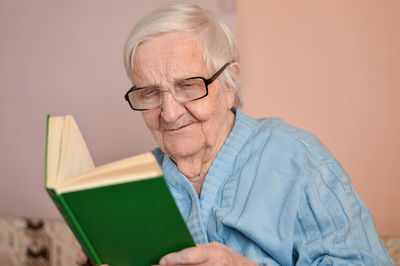 Old senior woman 90 years old holding open paper book in hands, reading best seller novel concept