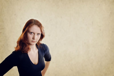 Portrait of angry young woman standing against wall