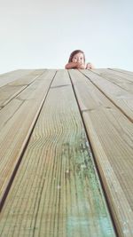Portrait of young woman on wooden floor against clear sky
