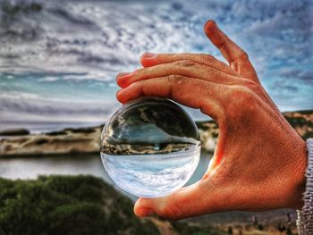 Midsection of person holding crystal ball in sea