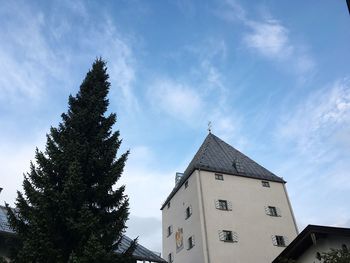 Low angle view of tree by building against sky