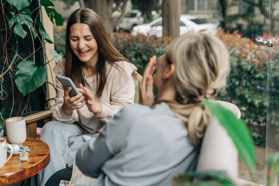 Smiling friends using mobile phone