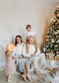 A family with children celebrate give gift boxes decorate a christmas tree in the interior the house