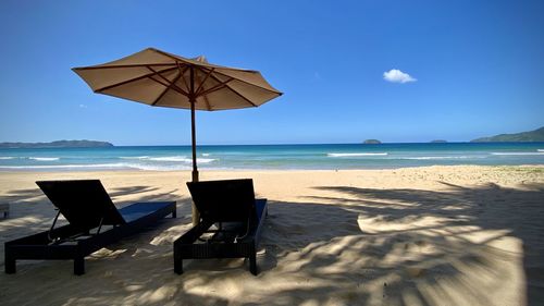 Deck chairs on beach against sky