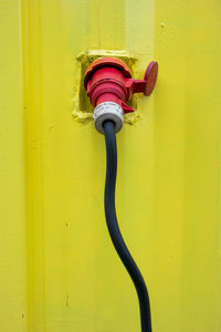 Close-up of yellow metal against wall