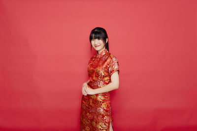 Portrait of a smiling young woman against red background
