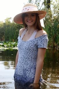 Portrait of beautiful woman standing against pond