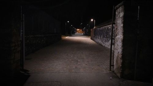 Empty alley amidst buildings at night