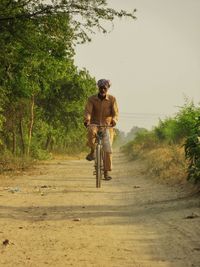 Man riding bicycle on road against trees