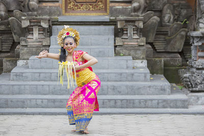 Woman in traditional clothing dancing against steps