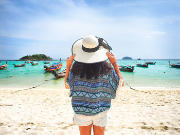Rear view of woman standing at beach against sky