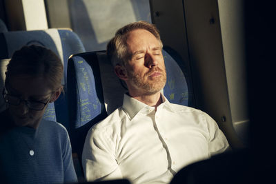 Man sitting in train with eyes closed