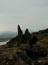 Rear view of man standing on rock against sky