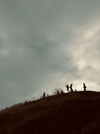 Silhouette people on land against sky