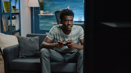 Portrait of young man sitting on sofa at home