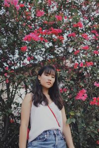 Portrait of beautiful young woman standing by flower plants