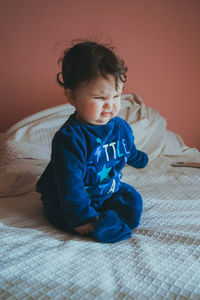 Cute girl sitting on bed at home