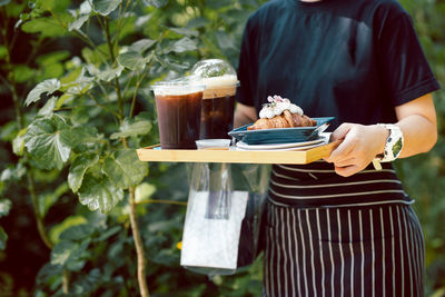 Waitress serving iced coffee and croissants in cafe outdoor.