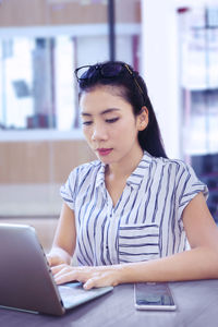 Young businesswoman using laptop in office