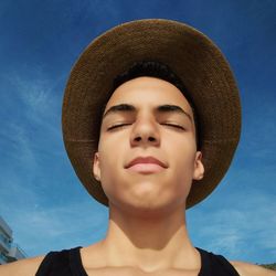 Portrait of teenage boy wearing hat against sky