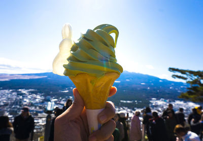 Close-up of hand holding ice cream against sky