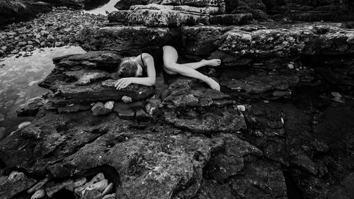 Young woman sitting on rock by water