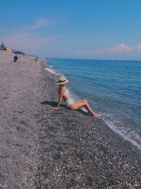 Side view of woman on beach against sky