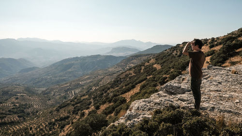 Man standing on rock against sky