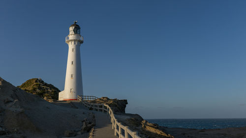 Lighthouse by sea against sky