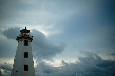 Low angle view of lighthouse by building against sky