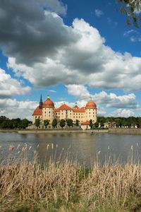 View of castle by lake against cloudy sky