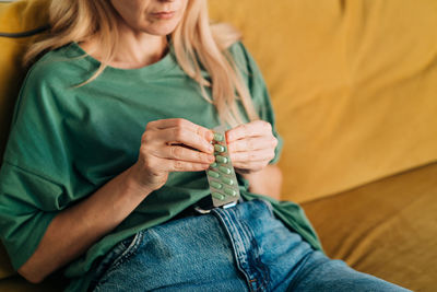 Unrecognizable woman holding a pack of headache pills.