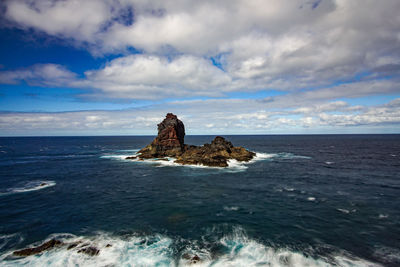 Rock formation in sea against sky