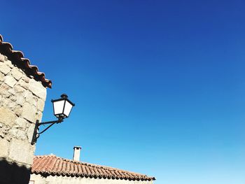 Low angle view of bird on roof against clear blue sky