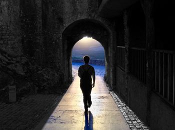 Rear view of silhouette man walking in tunnel