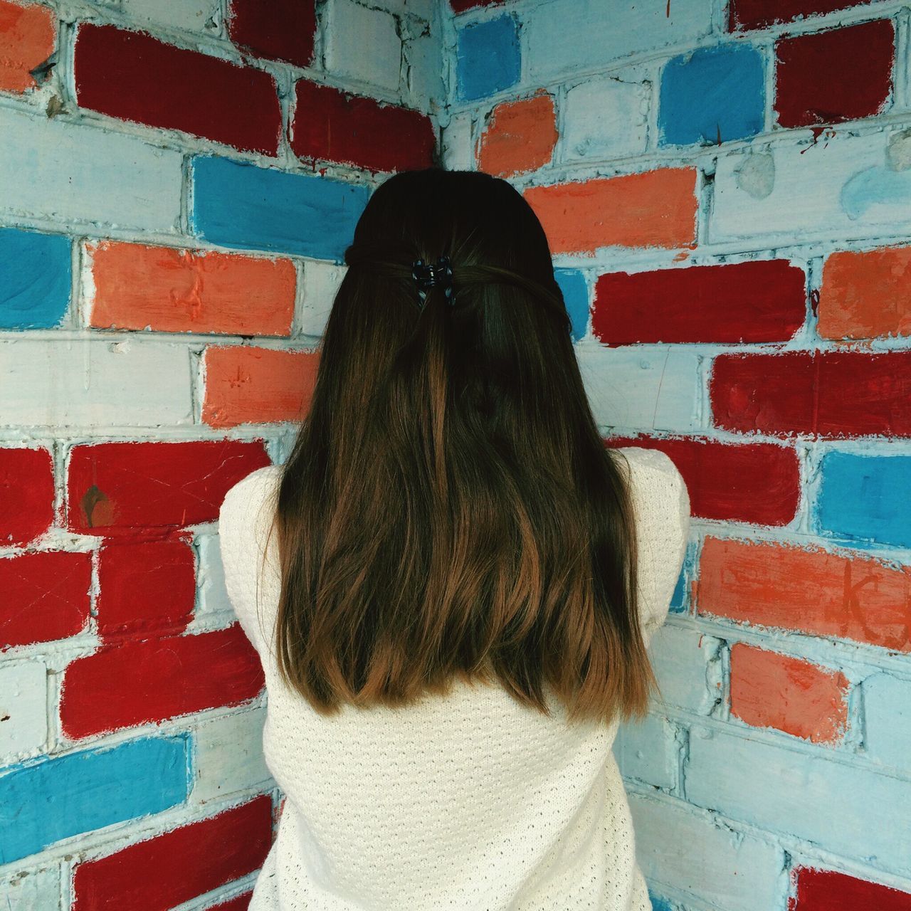 red, long hair, rear view, wall - building feature, architecture, built structure, person, brick wall, lifestyles, wall, leisure activity, standing, young women, building exterior, brown hair, day, casual clothing, side view