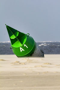 Close-up of green boat on beach against sky